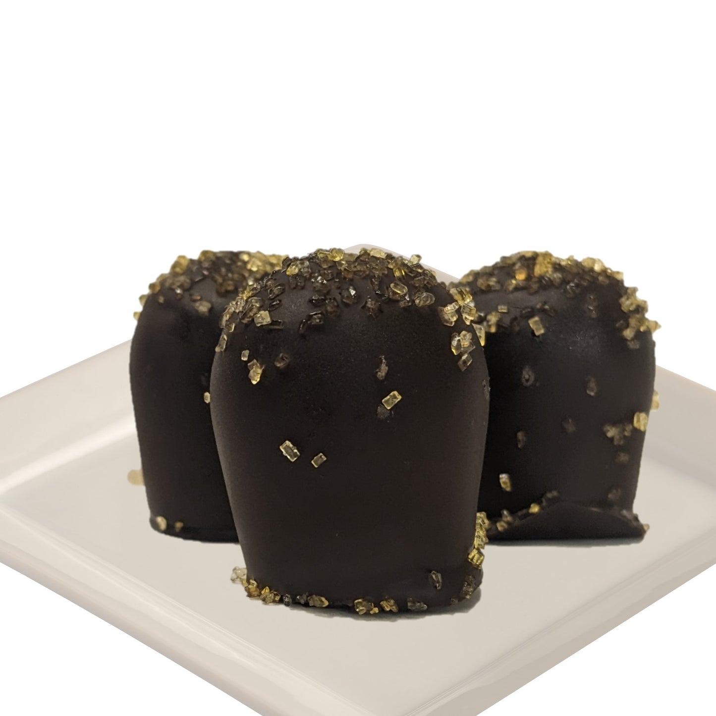 Three dark chocolate truffles with passionfruit flavor, garnished with gold flakes, on a white plate and a white background
