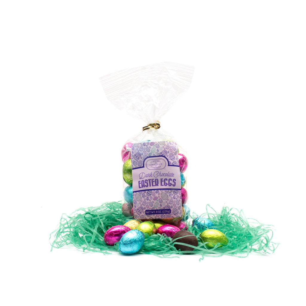 A clear package of dark chocolate mini eggs foiled in colorful spring colors, presented with decorative green grass and a Euphoria Chocolate Company label in front of a white background.