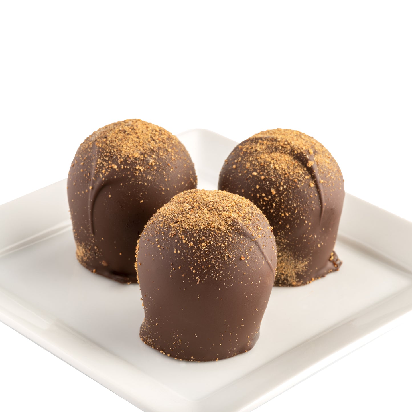 Three chocolate truffles with a dusting of cinnamon powder on top, placed on a white plate in front of a white background.