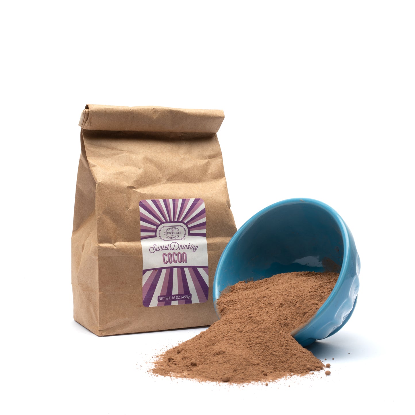 A paper bag labeled 'Euphoria Chocolate Company Sunset Drinking Cocoa' next to a blue bowl overflowing with cocoa powder.
