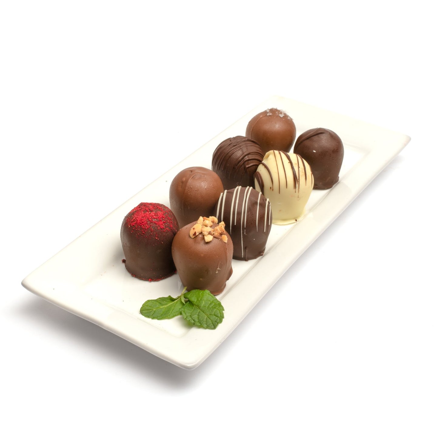 A selection of 8 classic chocolate truffles presented on a white plate, including assorted flavors such as raspberry, hazelnut, and mint against a white background.