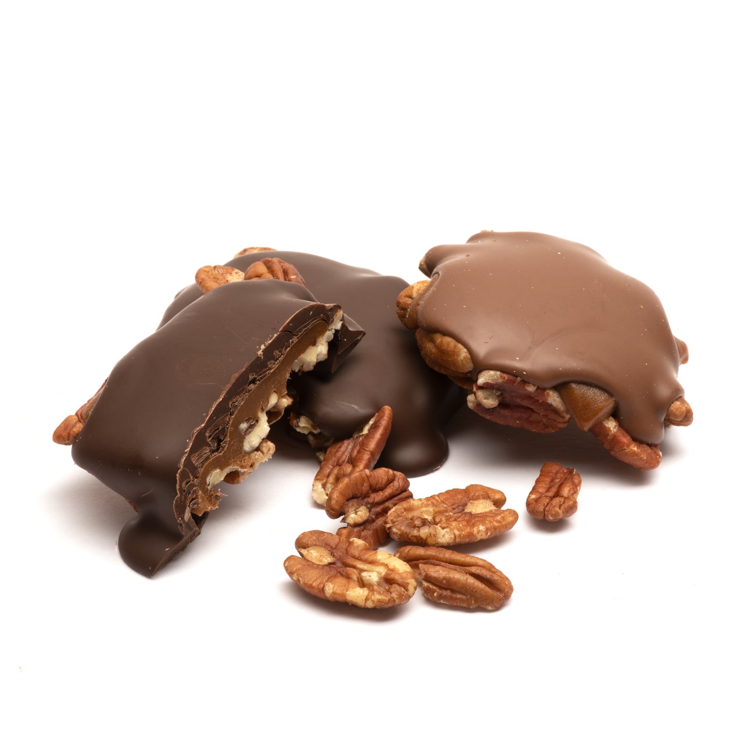 Pieces of dark and milk chocolate with visible pecans and caramel arranged on a white surface.