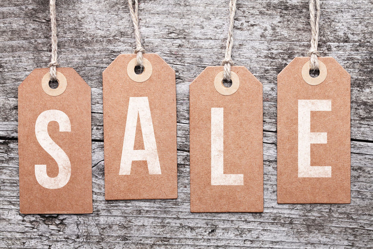 Paper tags reading "SALE" on a distressed wood background.