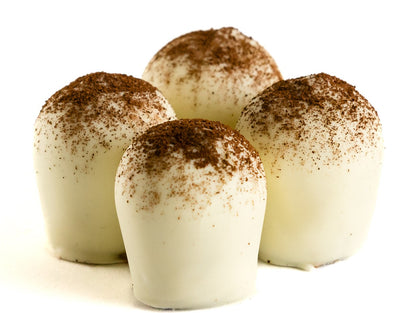 Four white chocolate truffles with cocoa powder dusting on white background