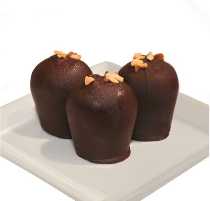 Three dark chocolate truffles with slivered almonds on top on a white plate against a white background.