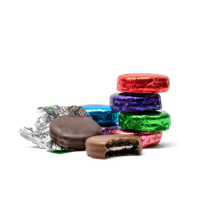 Assorted colorful chocolate-covered cookies on a white background with brightly-colored foil wrappers.