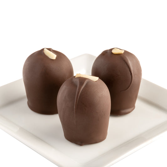 Three dark chocolate truffles with a hint of amaretto, each topped with a sliver of almond, presented on a white plate and white background