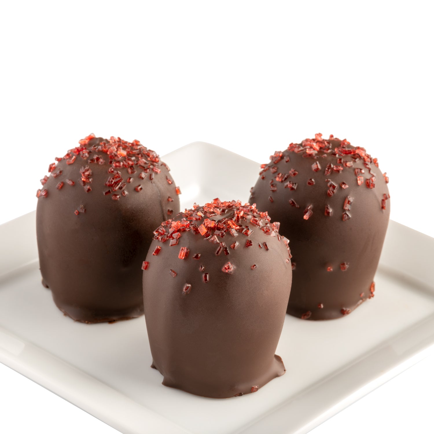 Three dark chocolate truffles with red flavor sprinkles on a white plate