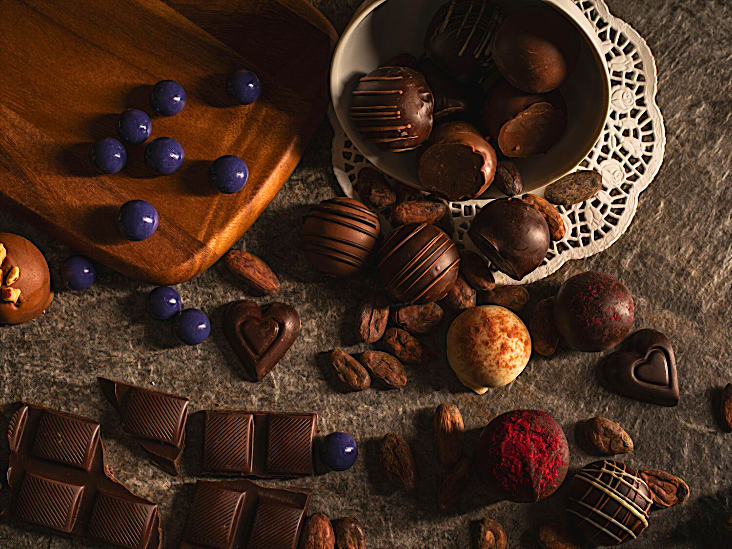 Assorted chocolates including truffles and bars on a textured surface.