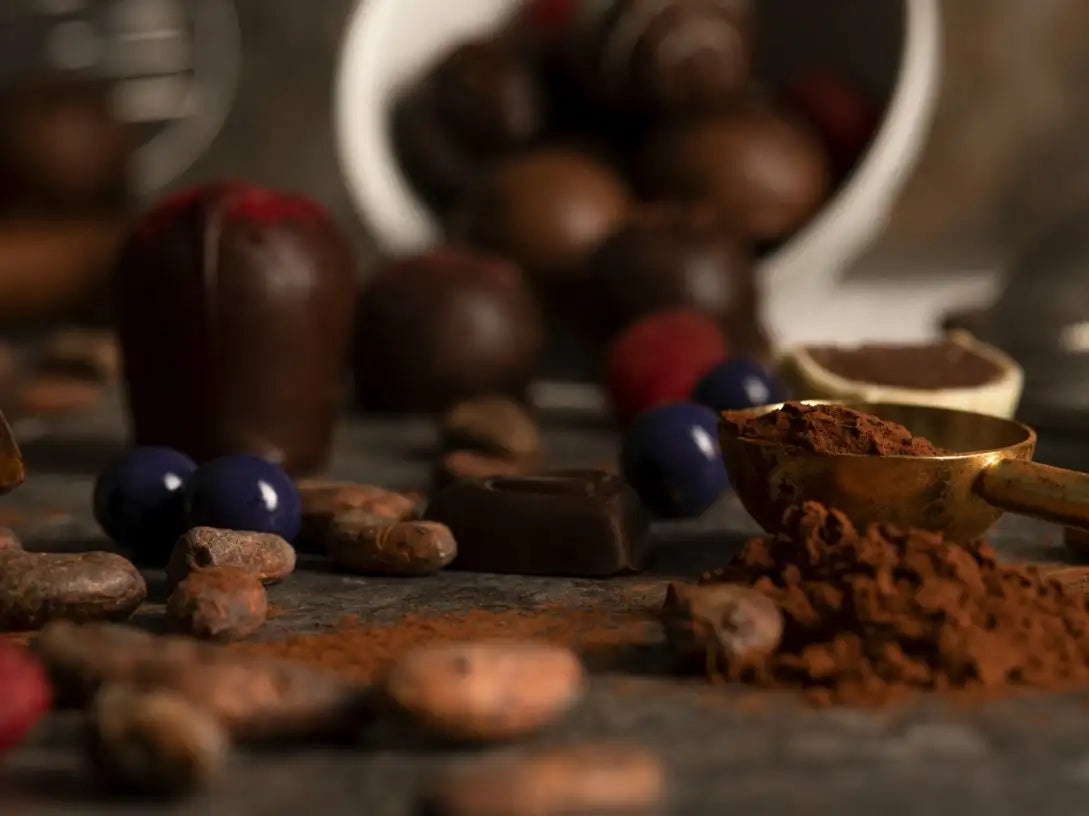 Assorted chocolate candies and cocoa powder on a dark surface with blurred background