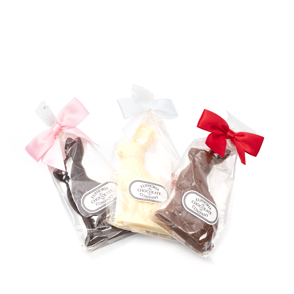 Three chocolate rabbits packaged in clear plastic, with decorative bows in pink and red. From left to right: white chocolate, milk chocolate, dark chocolate, all with the Euphoria Chocolate Company logo against a white background.
