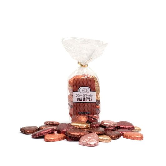 Individually wrapped dark chocolate leaves with a range of colors including green, golden yellow, orange, copper, brown, and red foil displayed in front of a clear packaging bag with a Euphoria Chocolate Company label.