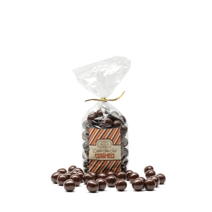 A clear plastic bag filled with round dark chocolate candies with a caramel and sea salt center, and sealed with a gold twist tie. A Euphoria Chocolate Company label on the front displays the product name.