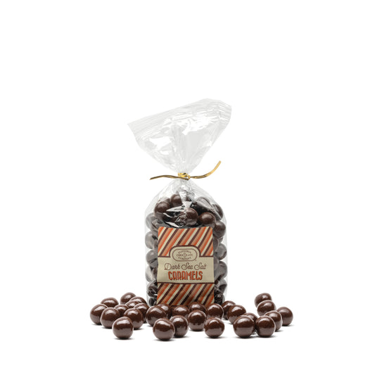 A clear plastic bag filled with round dark chocolate candies with a caramel and sea salt center, and sealed with a gold twist tie. A Euphoria Chocolate Company label on the front displays the product name.