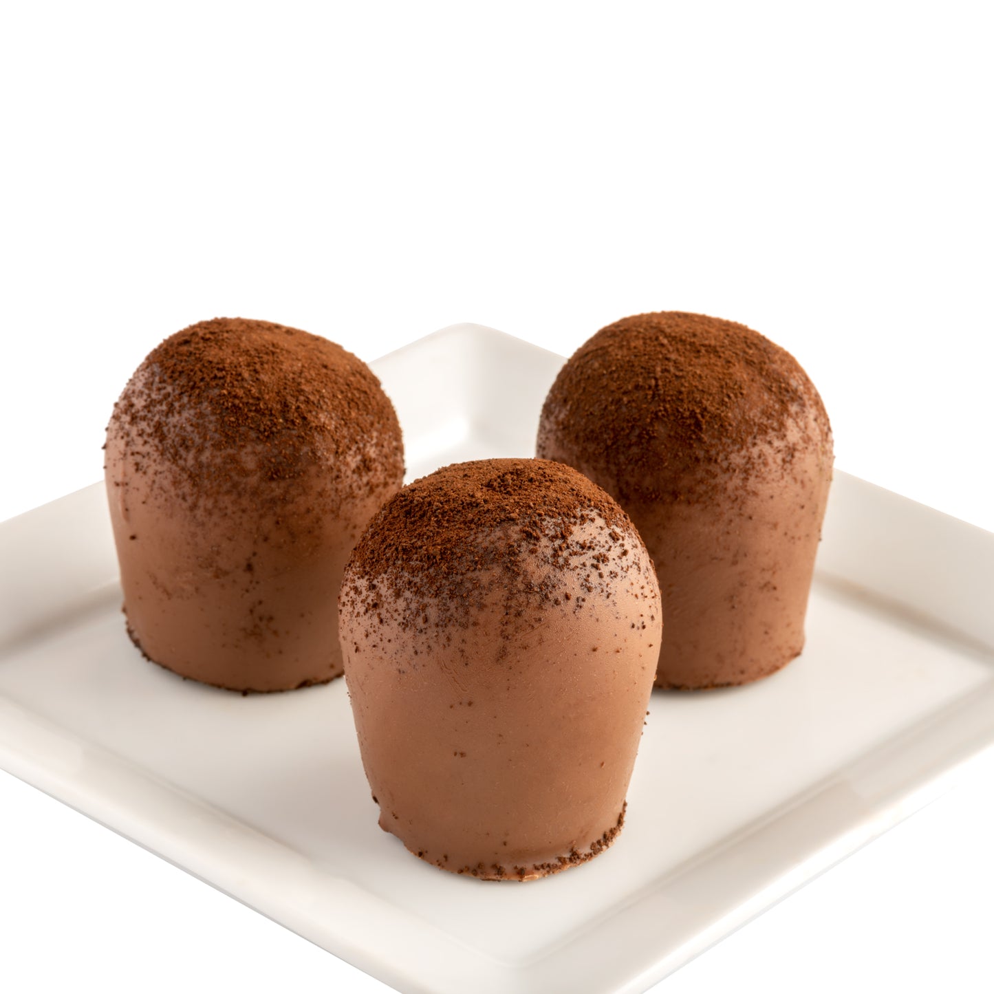 Three chocolate truffles with a sprinkle of ground coffee on top, presented on a white plate with a white background.