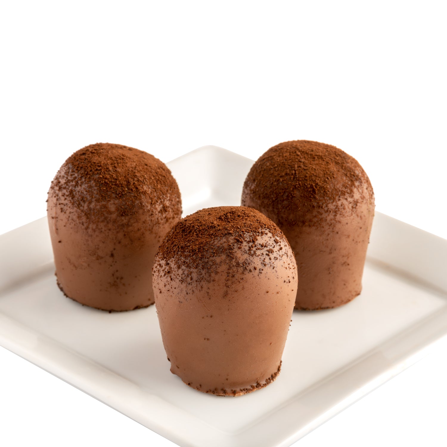 Three chocolate truffles with a sprinkle of ground coffee on top, presented on a white plate with a white background.