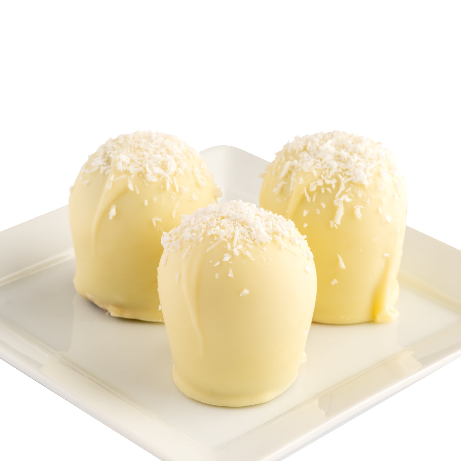 Three white chocolate truffles with shredded coconut on top. The truffles are on a white plate in front of a white background.