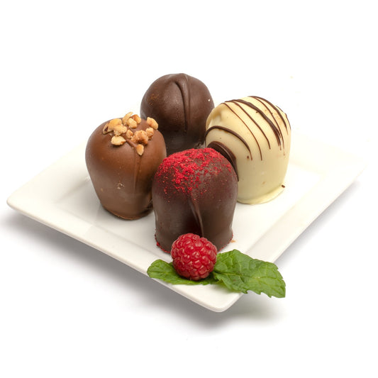 A selection of 4 classic chocolate truffles presented on a white plate, including assorted flavors such as raspberry, hazelnut, and double chocolate against a white background.