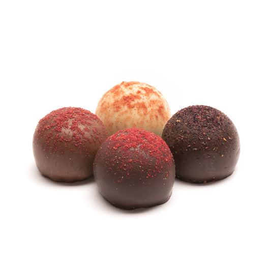 An assortment of 4 chocolate truffles in various berry wine flavors. The truffles are coated in milk, dark, and white chocolate and are dusted with powdered freeze-dried berries in front of a white background.