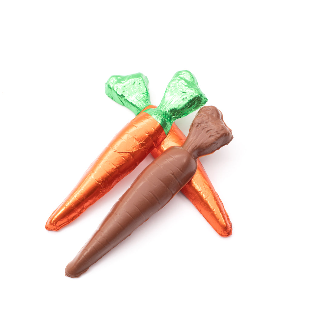 Two chocolate carrots with green and orange foil wrappers on a white background. One item is unwrapped, showing a milk chocolate carrot with texturized detail.