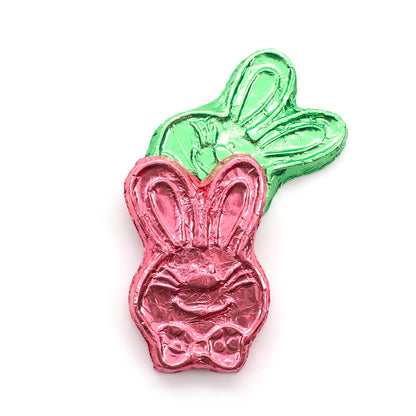 Two hand foiled chocolate bunny heads, one with green foil and the other with pink foil.